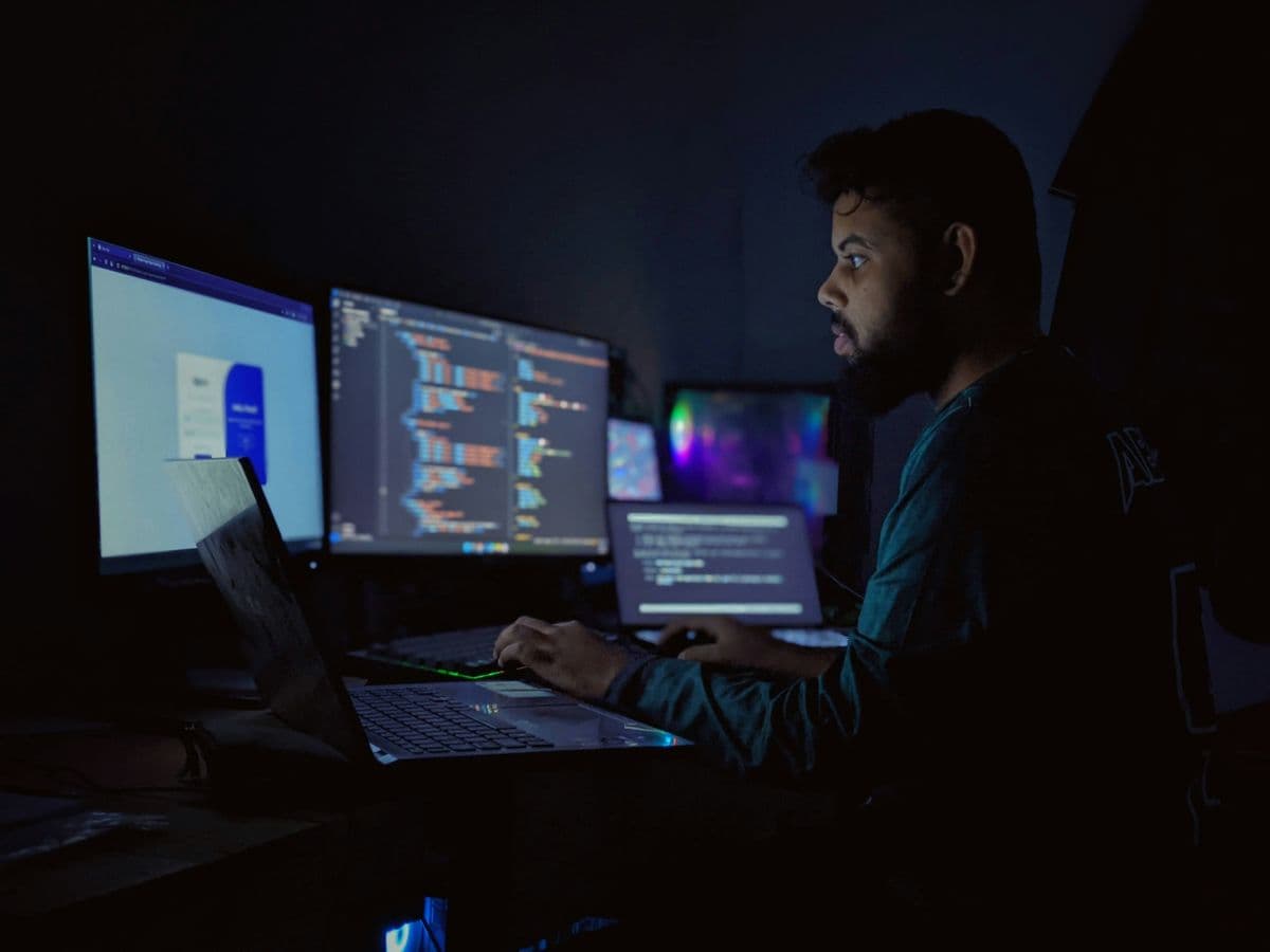 Desenvolvedor trabalhando em múltiplos monitores com código