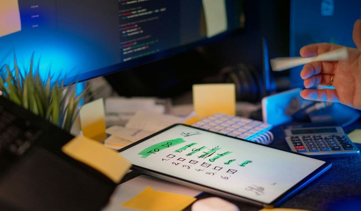 Mesa de trabalho com tablet, anotações e monitores